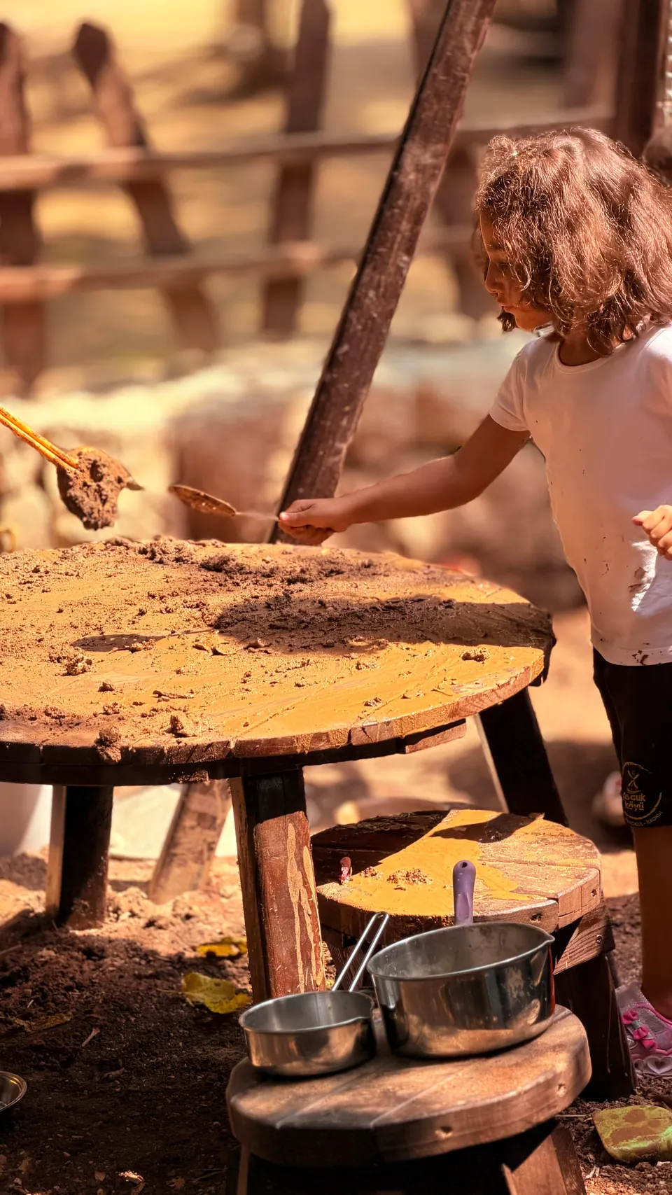 Çamurla kaplı ahşap masada oyun oynayan çocuk